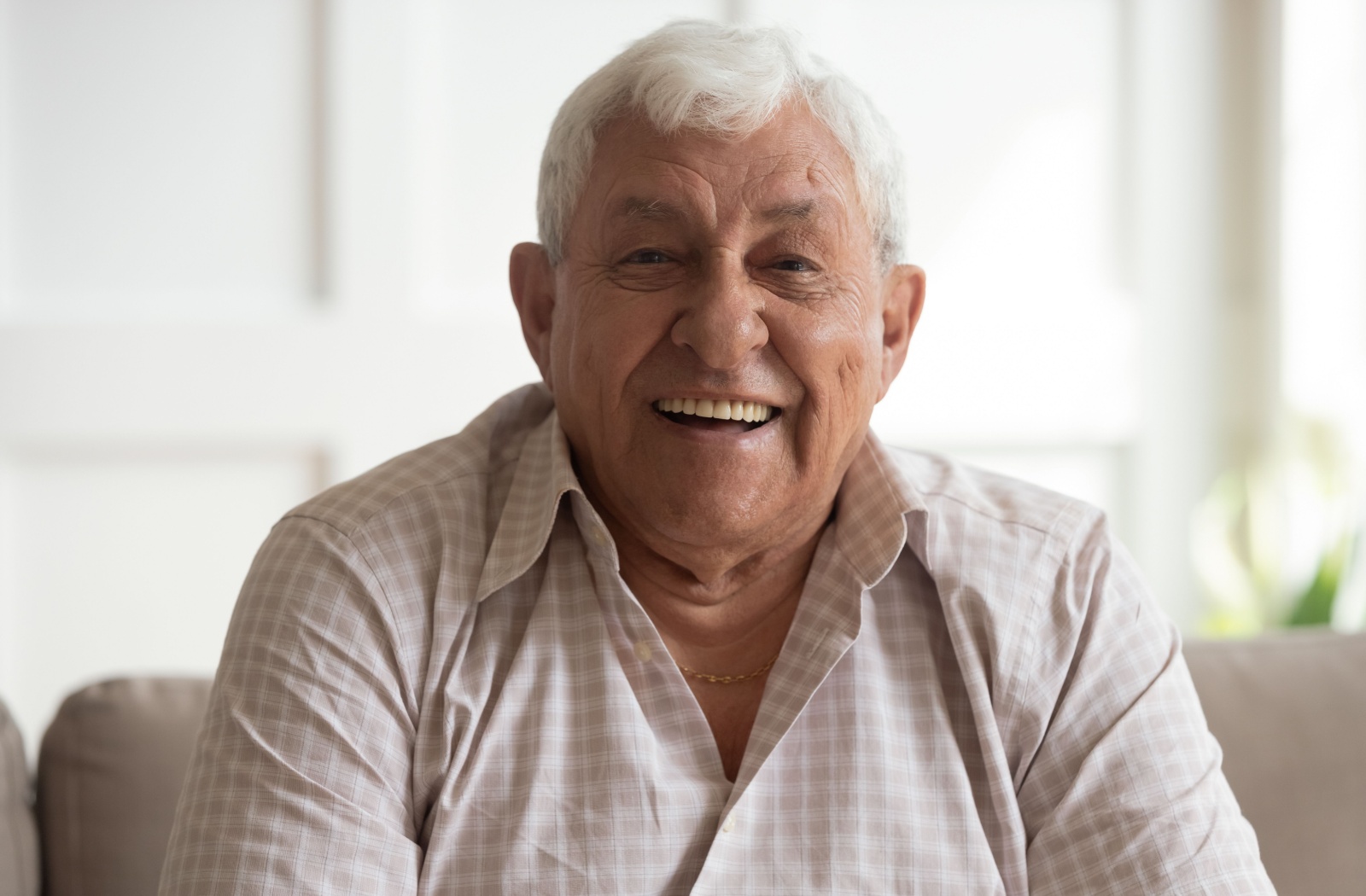 A close-up of an older adult with dementia smiling at the camera while in memory care.