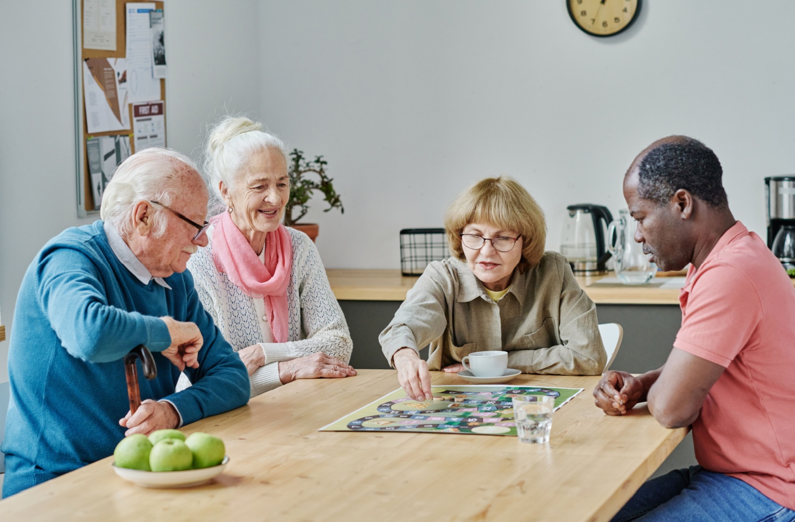 A group of happy seniors enjoys a board game together in their community's common area.
