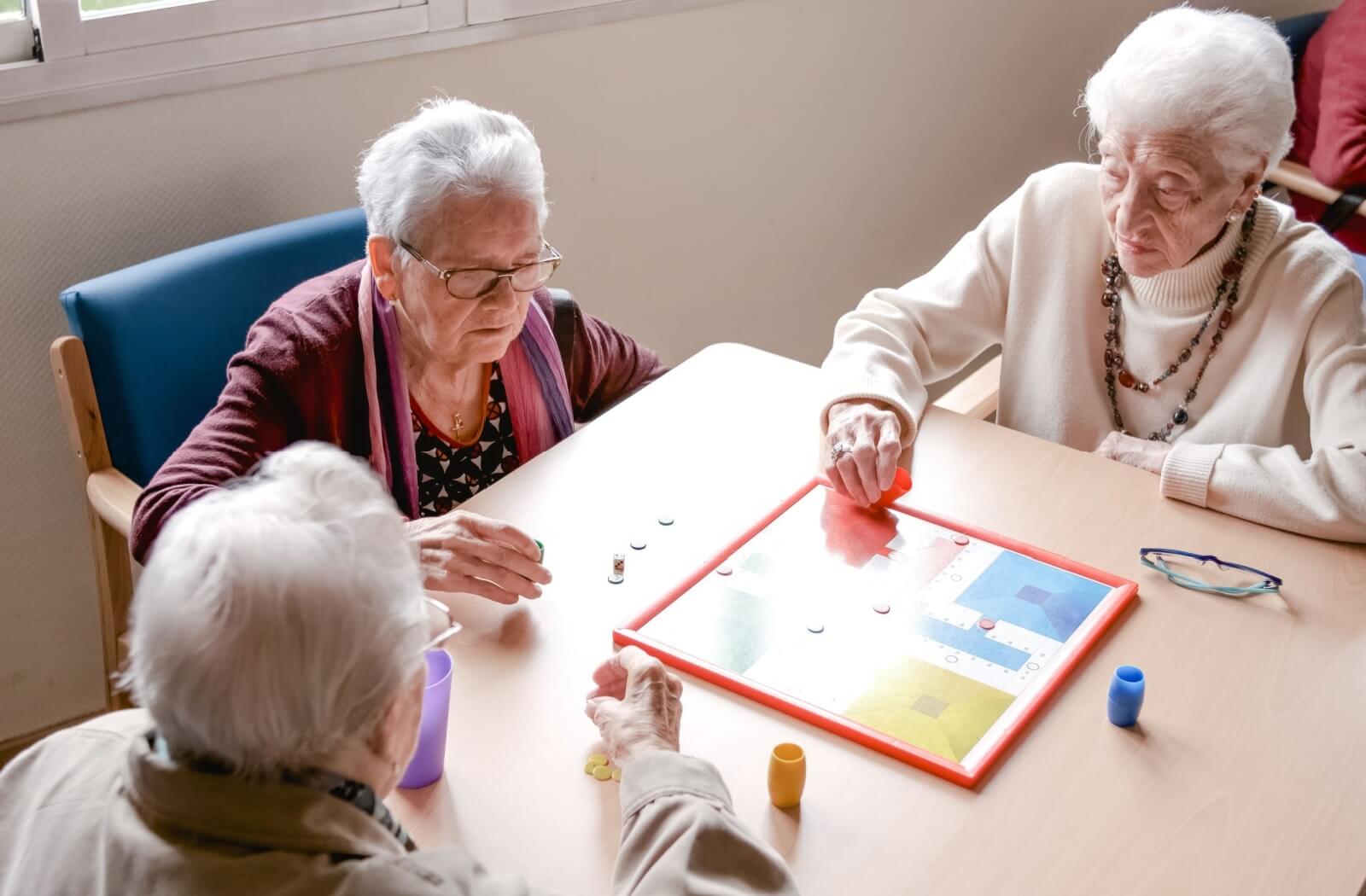A group of seniors play a board game during their time together at a senior day center.
