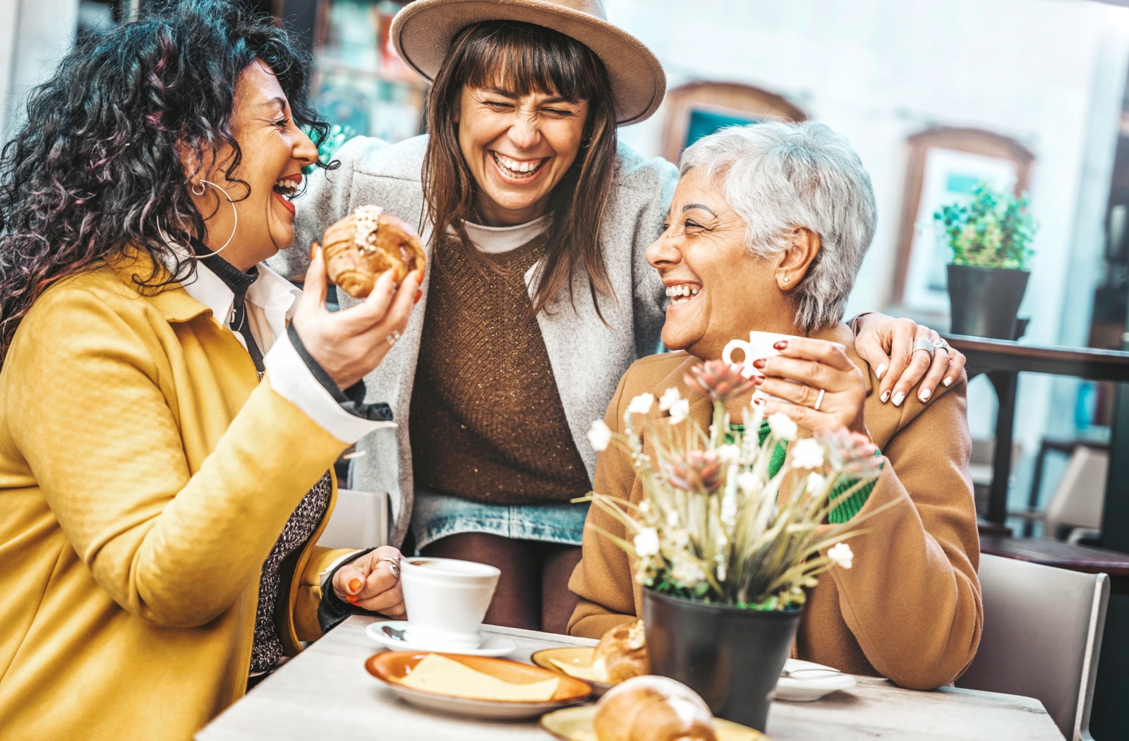 Three women in personal care laugh together over coffee.