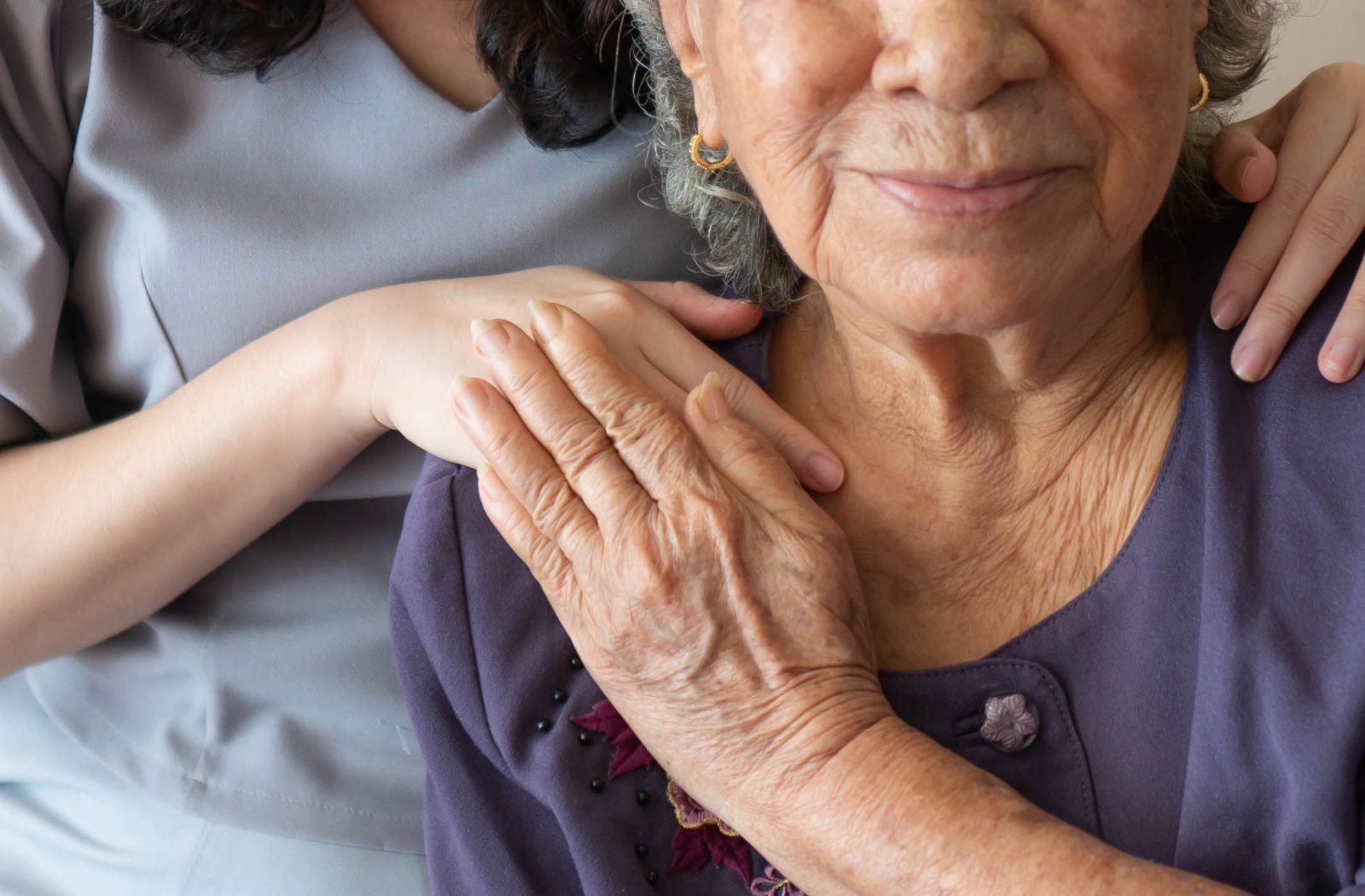 Close up of a caregiver resting a hand on a senior's shoulder